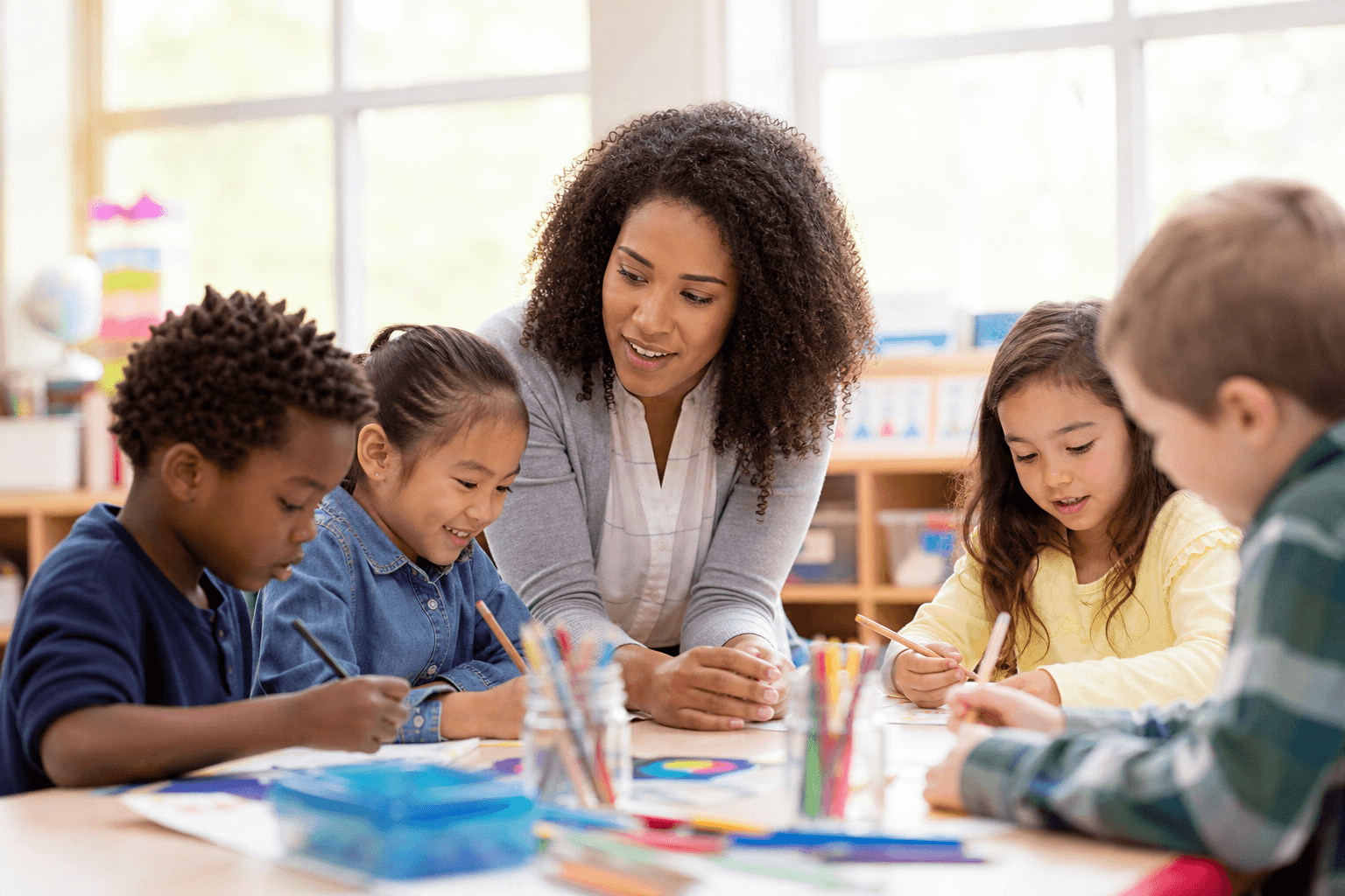 A teacher supporting kindergarten through 2nd grade students in a classroom